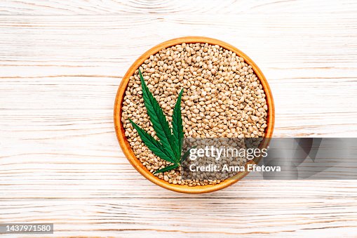 Cannabis leaf and hemp seeds in bowl on wooden background. Concept of using healthy food supplements. Photography from above Cannabis leaf and hemp seeds in bowl on wooden background. Concept of using healthy food supplements. Photography from above