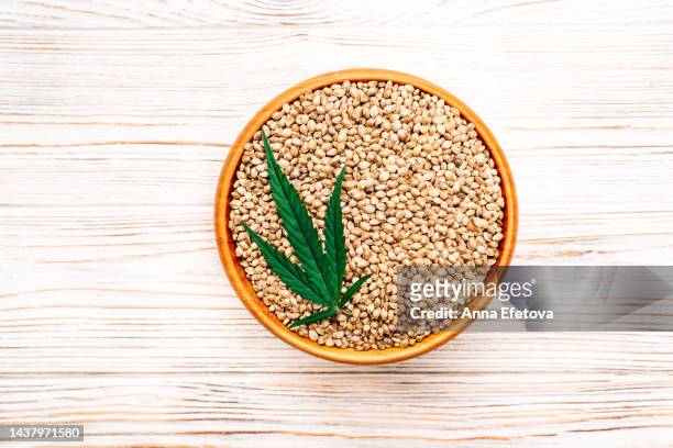 cannabis leaf and hemp seeds in bowl on wooden background. concept of using healthy food supplements. photography from above - hemp seed 個照片及圖片檔