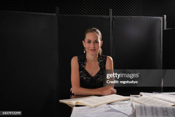 mature pianist woman posing  at camera near piano - klassisk musiker bildbanksfoton och bilder