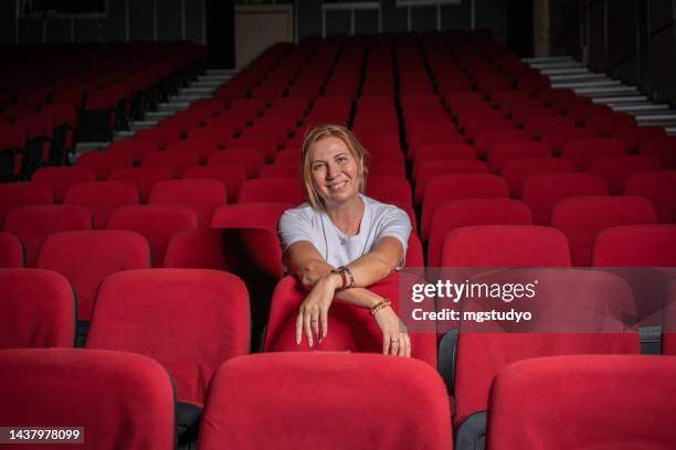 mature screenwriter director woman sitting alone in theater cinema - scriptwriter stock pictures, royalty-free photos & images