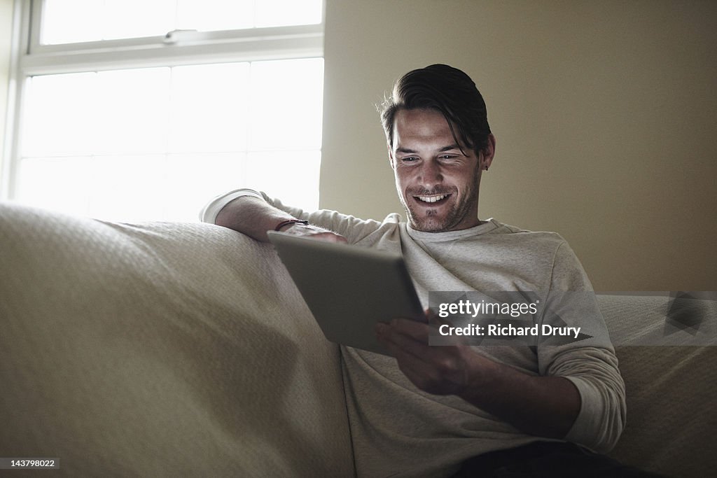 Young man on sofa using digital tablet