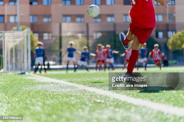 soccer player kicking the ball from the corner to his team near the opponent's goal with opponents - children sports league stock pictures, royalty-free photos & images