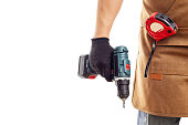 Man in apron and gloves holds cordless screwdriver on white background