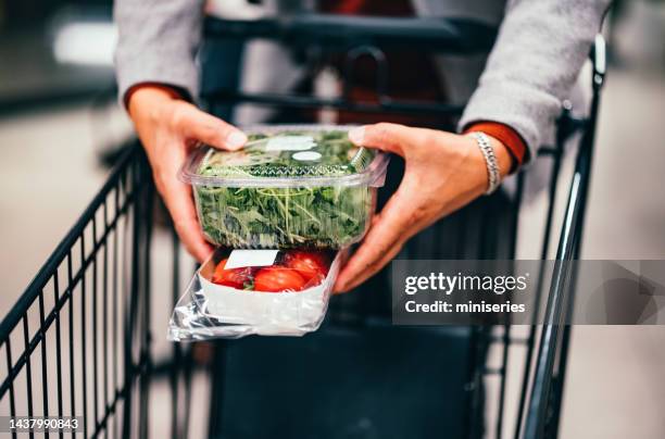 hombre anónimo colocando verduras en el carrito de compras - posicionamiento fotografías e imágenes de stock