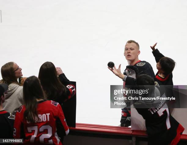 Brady Tkachuk of the Ottawa Senators tosses a puck to a fan during warmups prior to a game against the Dallas Stars at Canadian Tire Centre on...