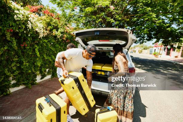 wide shot of family loading rental car with luggage while on vacation - wide load stock pictures, royalty-free photos & images