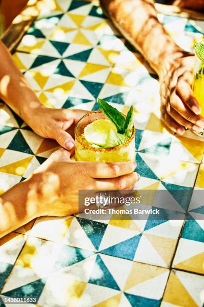 medium shot of womans hands holding margarita at table in beach cafe - margarita stockfoto's en -beelden