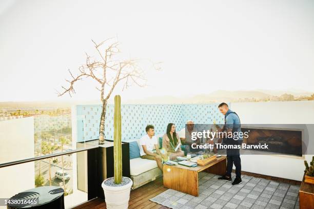 wide shot of waiter bringing drinks to family dining at outdoor restaurant - baja california sur stock-fotos und bilder