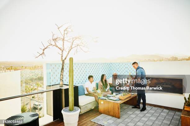 wide shot of waiter bringing drinks to family dining at outdoor restaurant - rooftop dining foto e immagini stock