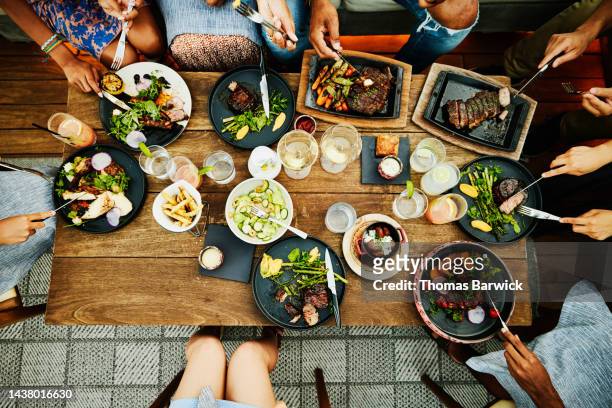 medium overhead shot of families sharing dinner at outdoor restaurant - teller draufsicht stock-fotos und bilder
