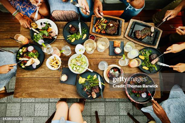 medium overhead shot of families sharing dinner at outdoor restaurant - hora de comer fotografías e imágenes de stock