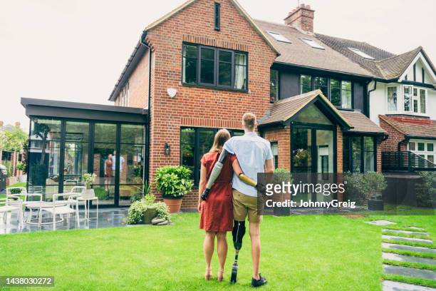proud young homeowners admiring their modern brick house - new home pov stock pictures, royalty-free photos & images