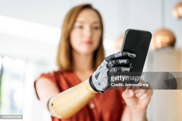 バイオニックアームを着てスマートフォンを使用する白人女性 - bionic hand ストックフォトと画像