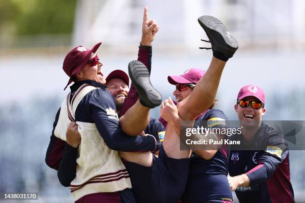 Andy Bichel, assistant Queensland coach is thrown into the air by players while warming up during the Sheffield Shield match between Western...