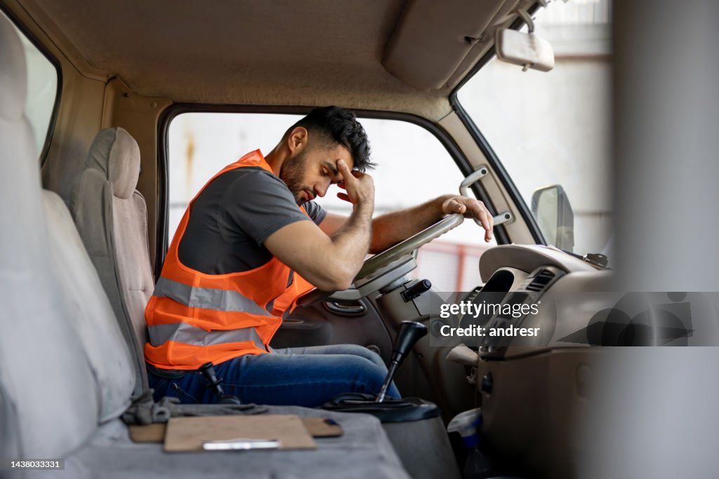 Conductor de camión cansado que tiene dolor de cabeza después de trabajar horas extras