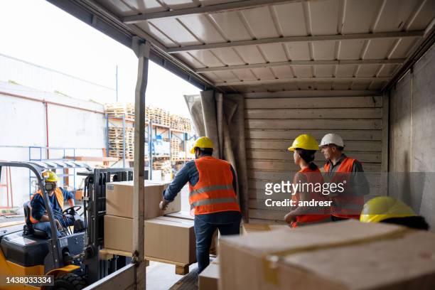 workers unloading packages from a truck while while working at a distribution warehouse - freight truck loading stock pictures, royalty-free photos & images