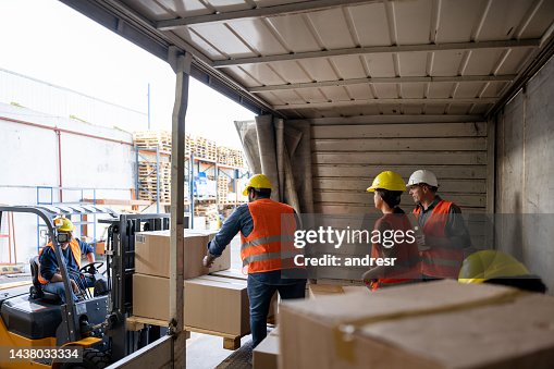 Workers unloading packages from a truck while while working at a distribution warehouse Workers unloading packages from a truck while while working at a distribution warehouse
