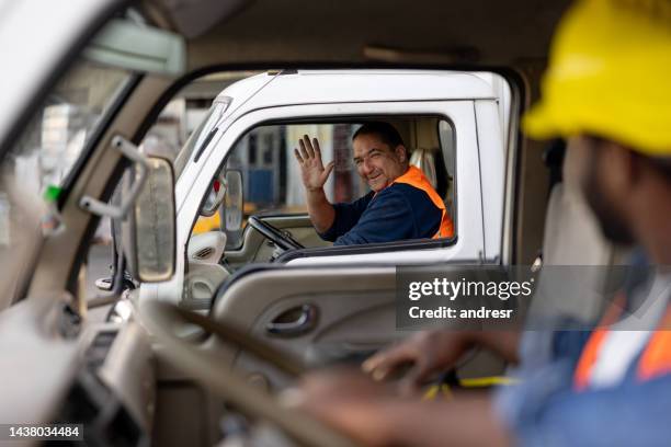 happy truck driver greeting another one while driving - zwaaien gebaren stockfoto's en -beelden