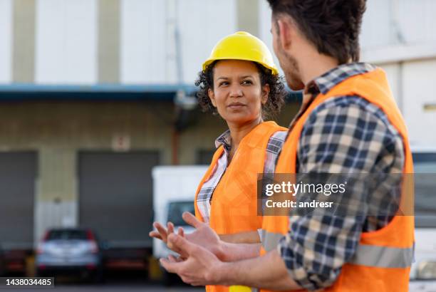 latin american workers talking while working at a distribution warehouse - organisation culture stock pictures, royalty-free photos & images