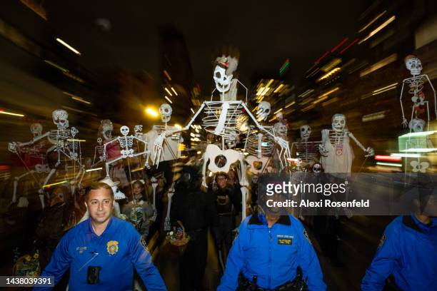 Members of the NYPD walk in front of people dressed in costume controlling puppet skeletons in New York City’s 49th Annual Village Halloween Parade...