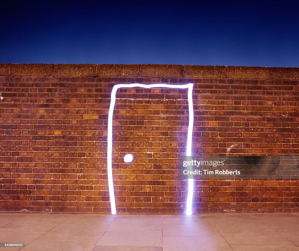 Door made of light on brick wall.