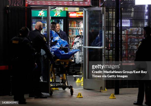 Oakland police investigate a fatal shooting as members of the Alameda County Coroners Bureau remove a body at Ali Babas Smoke Shop on International...