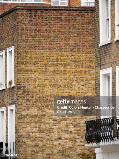 weathered brown brick facades and gable with windows and balcony in london - de media stock pictures, royalty-free photos & images