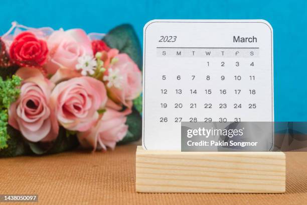 calendar desk 2023: march is the month for the organizer to plan and deadline with a flower handcrafted against a blue paper background. - marzo fotografías e imágenes de stock