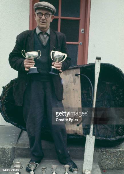 Man with a selection of trophies standing by his coracle near the River Teifi in Wales, circa 1970.