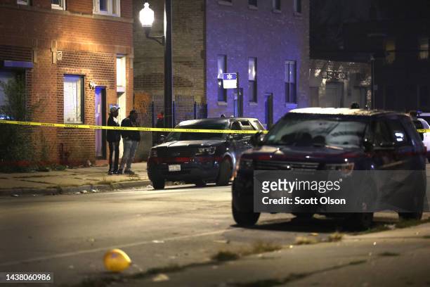 People watch as police investigate the scene where as many as 14 people were reported to have been shot on October 31, 2022 in Chicago, Illinois....