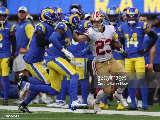 Christian McCaffrey of the San Francisco 49ers runs down the sidelines as he is chased by Nick Scott and Derion Kendrick of the Los Angeles Rams at...
