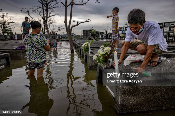 Man lights a candle at the tomb of a departed loved one at a flooded cemetery following Tropical Storm Nalgae, as Filipinos mark All Saints' Day on...