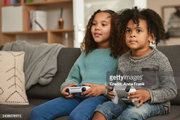 young siblings playing video games together - kids winning stock pictures, royalty-free photos & images