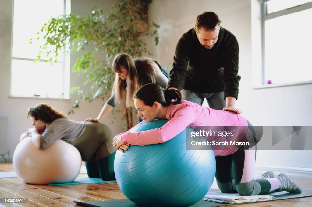 Pregnant women and birthing partners learning massage techniques in birth preparation workshop