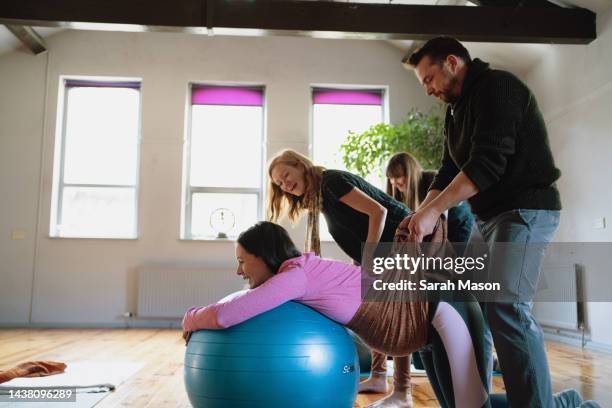 male birthing partner supporting partner's pregnant belly with scarf - yoga ball work 個照片及圖片檔