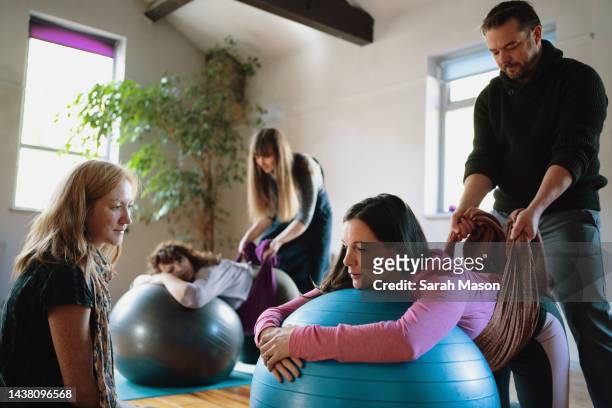 birthing partners learn how to support partner's pregnant bellies with scarf - pregnancy class stockfoto's en -beelden