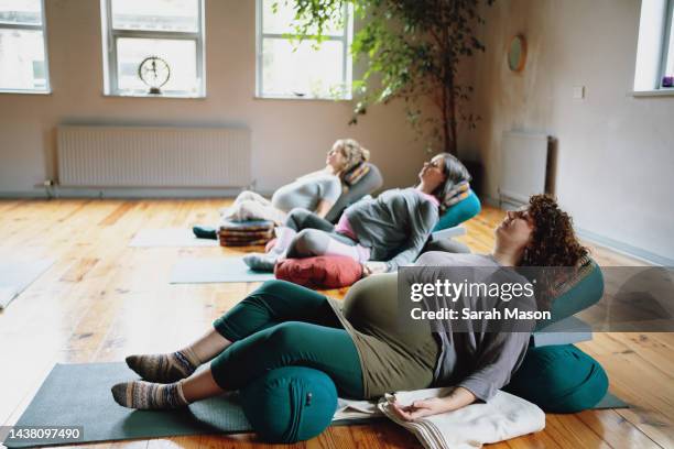 three pregnant women lying back on yoga mats meditating - yoga prop stock pictures, royalty-free photos & images