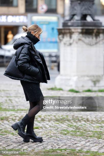 Influencer Gitta Banko wearing a black knitted turtleneck mini dress by Iris von Arnim, a black puffer jacket by Margiela, black tight by Wolford,...