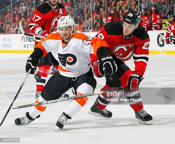 Eric Wellwood of the Philadelphia Flyers eyes the puck while being defended by Mark Fayne of the New Jersey Devils in Game Three of the Eastern...
