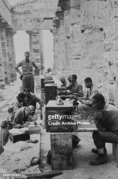 Company of US Military personnel (seated behind desk in the their temporary 'office' between the columns of the ancient Second Temple of Hera , a...