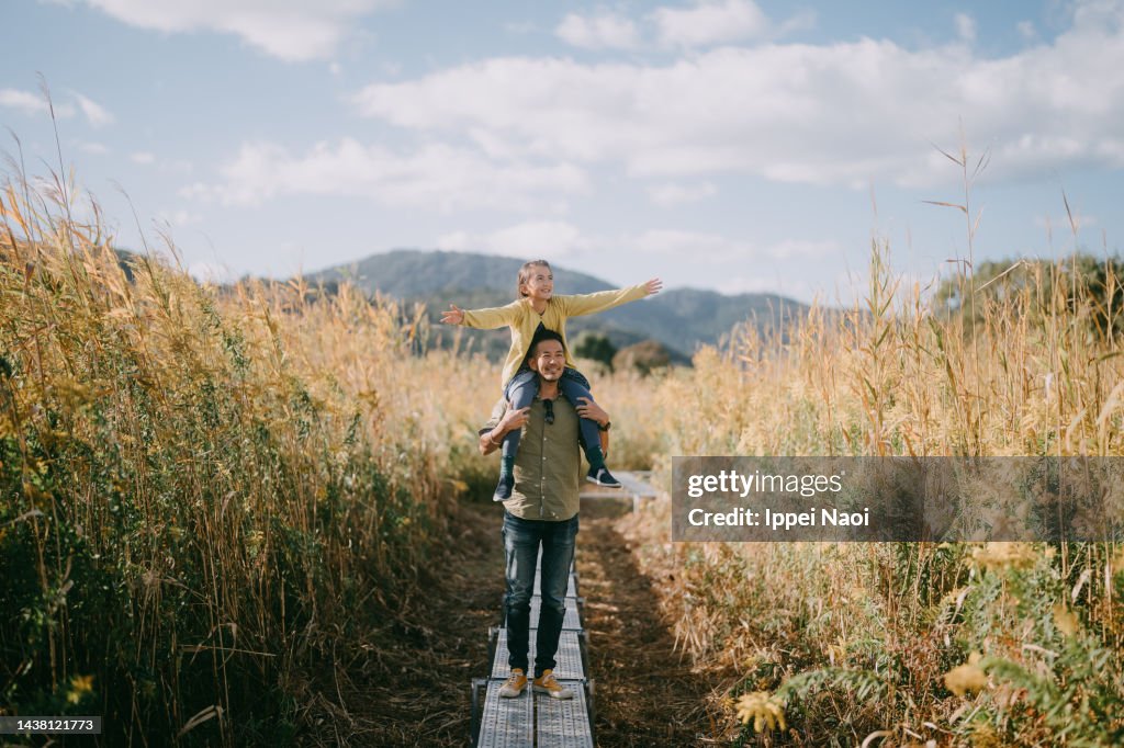 Father carrying child on shoulders in autumn
