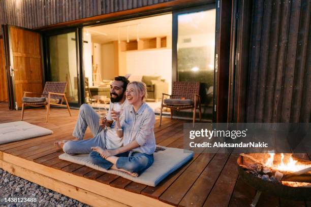 young couple drinking wine by the fire pit - terrace stockfoto's en -beelden