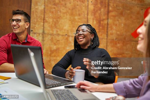 young modern businesswoman in coworking space laughing with her colleagues while working - coworkers having fun stock pictures, royalty-free photos & images