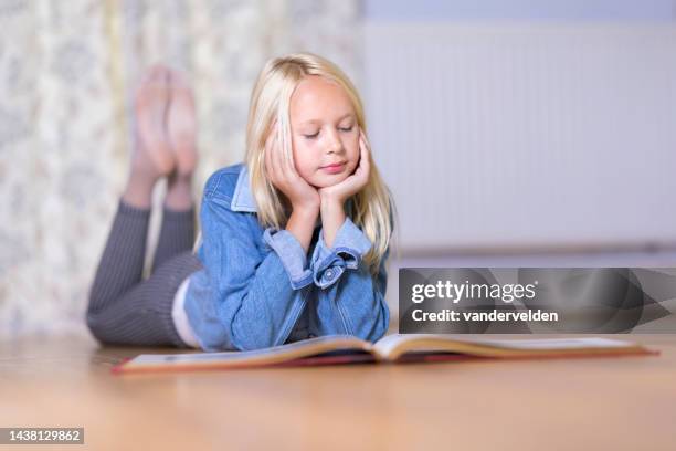 fair haired young girl lying on the floor reading - child reading book stock pictures, royalty-free photos & images