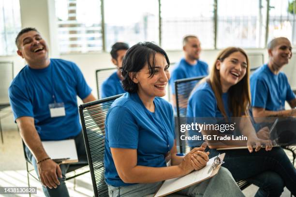 volunteers paying attention and smiling on a community center presentation - charity benefit stock pictures, royalty-free photos & images