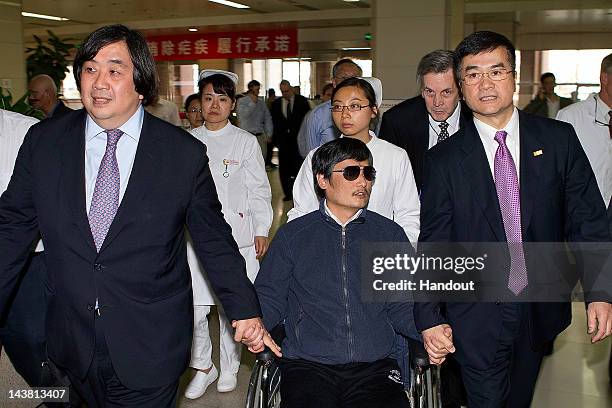 In this handout photograph provided by the U.S. Embassy Beijing press office, Chinese dissident Chen Guangcheng holds hands with U.S. Ambassador to...