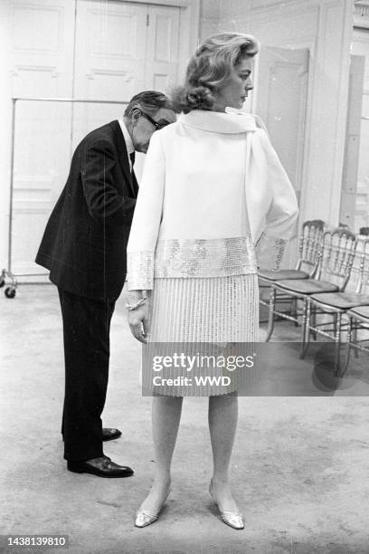 Lauren Bacall with Norman Norell trying on her Spring wardrobe at the Norell showroom in New York