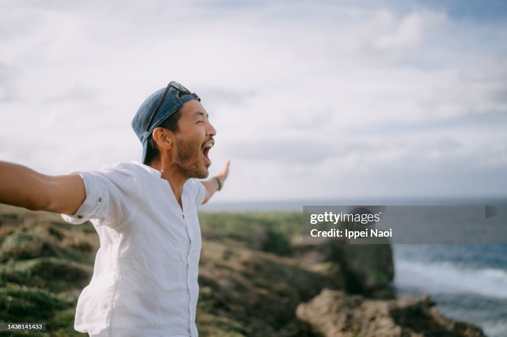Man shouting on top of cliff by sea