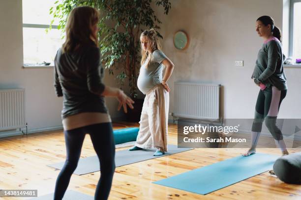 women standing in pregnancy yoga class - pregnancy class stock-fotos und bilder