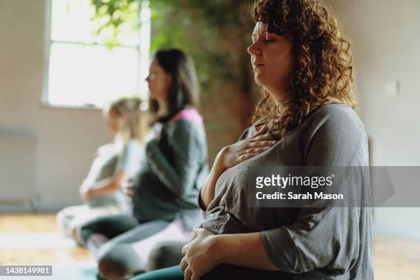 pregnant women sat in yoga class meditating - yoga prop stock pictures, royalty-free photos & images